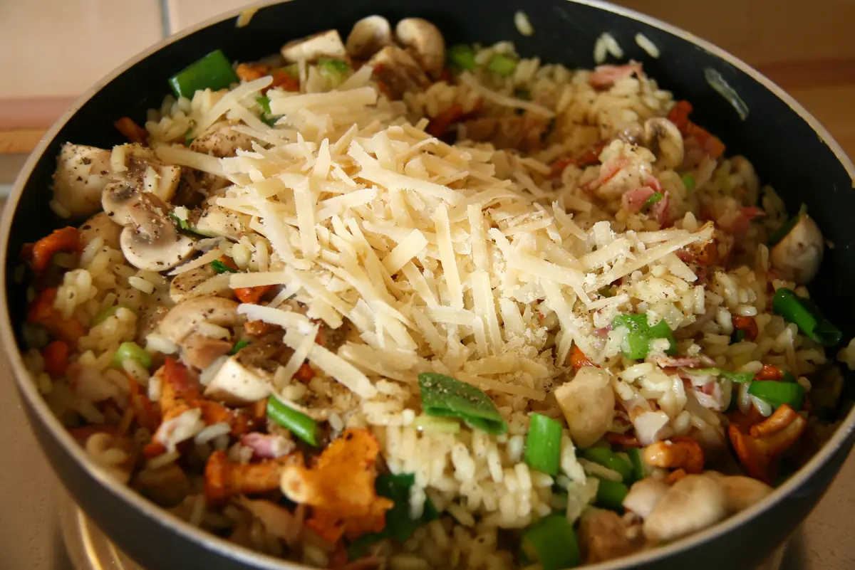 Risotto med svamp, grönsaker och riven ost i en stekpanna